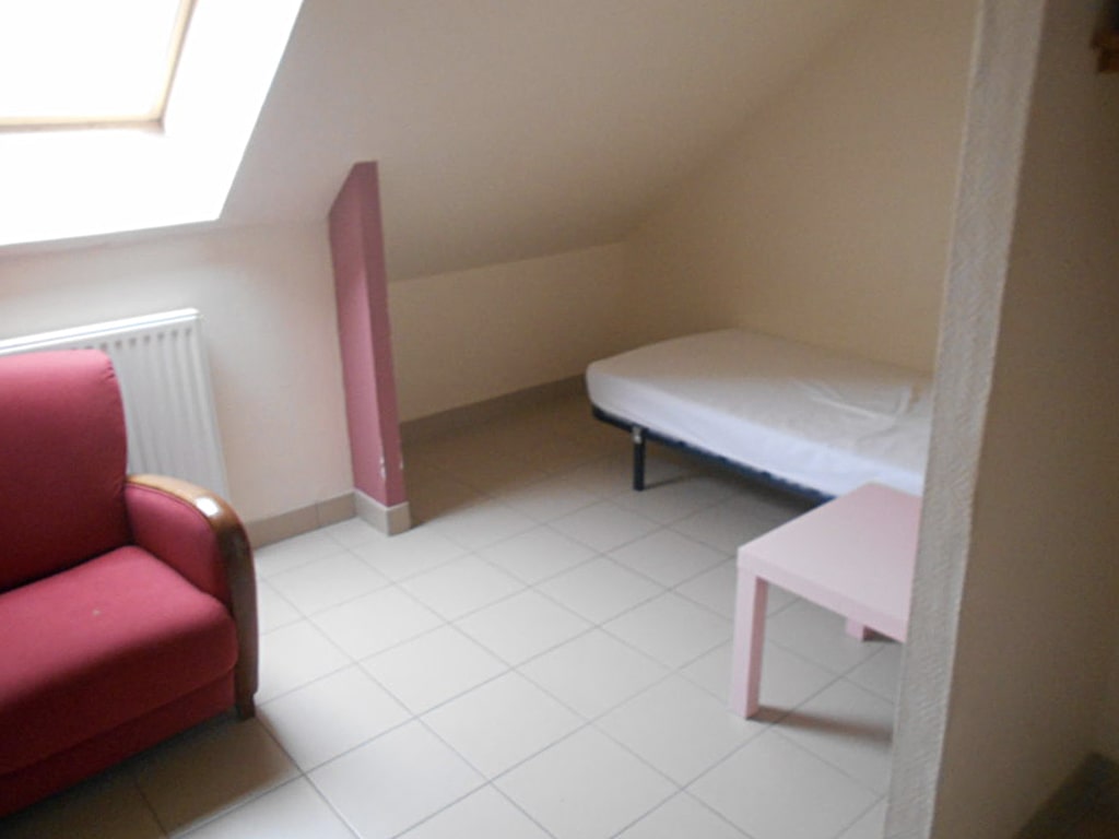 photo d'une chambre sous les toits, avec un lit simple, table de chevet rose, mur rose et mur blanc, radiateur, lucarne de toit, du gîte de groupe et maison d'hôtes du Bas Mena